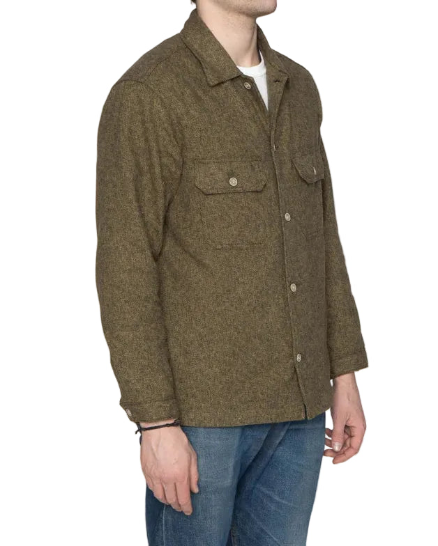 Man wearing a green jacket and blue jeans against a white background