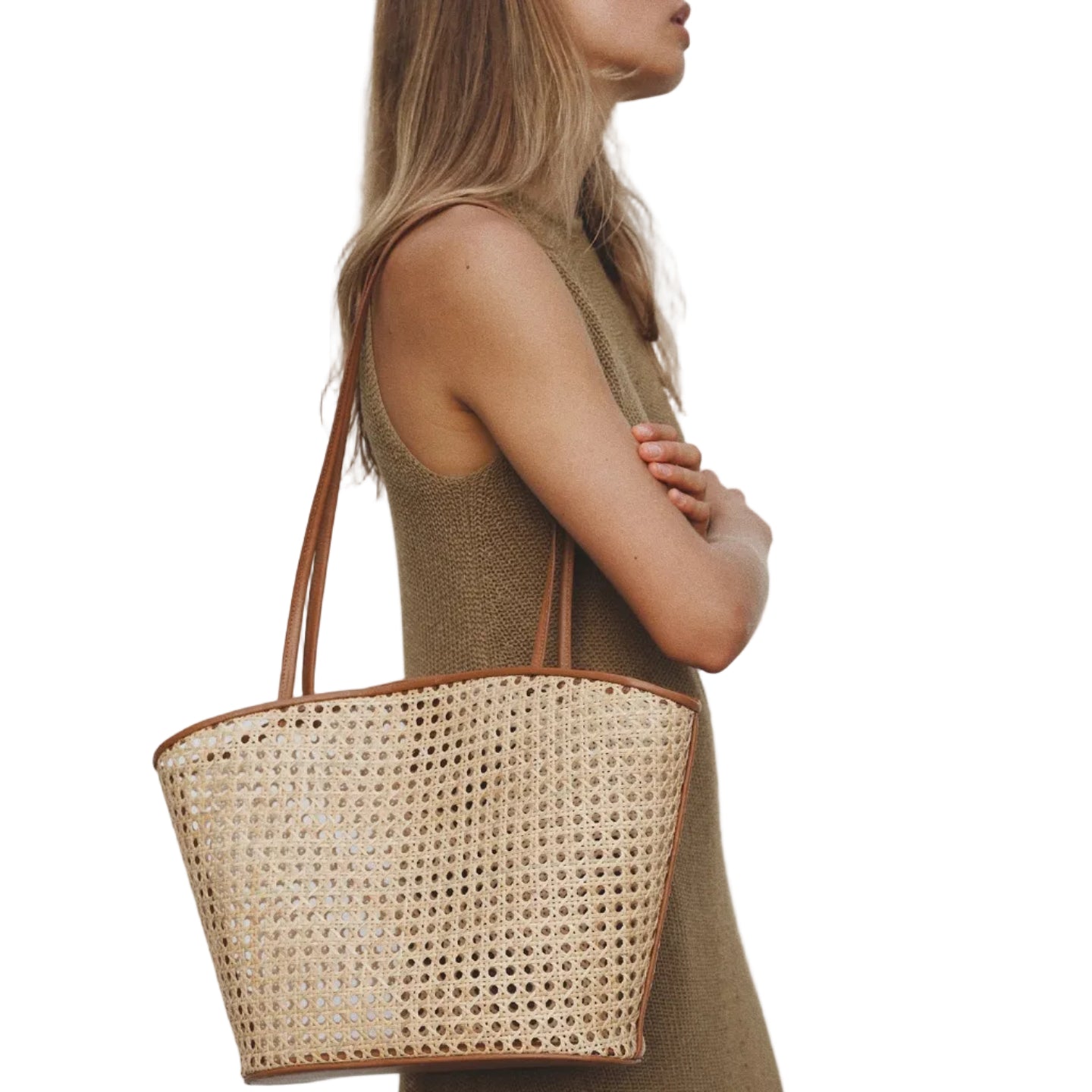 Woman holding a woven handbag against a plain background