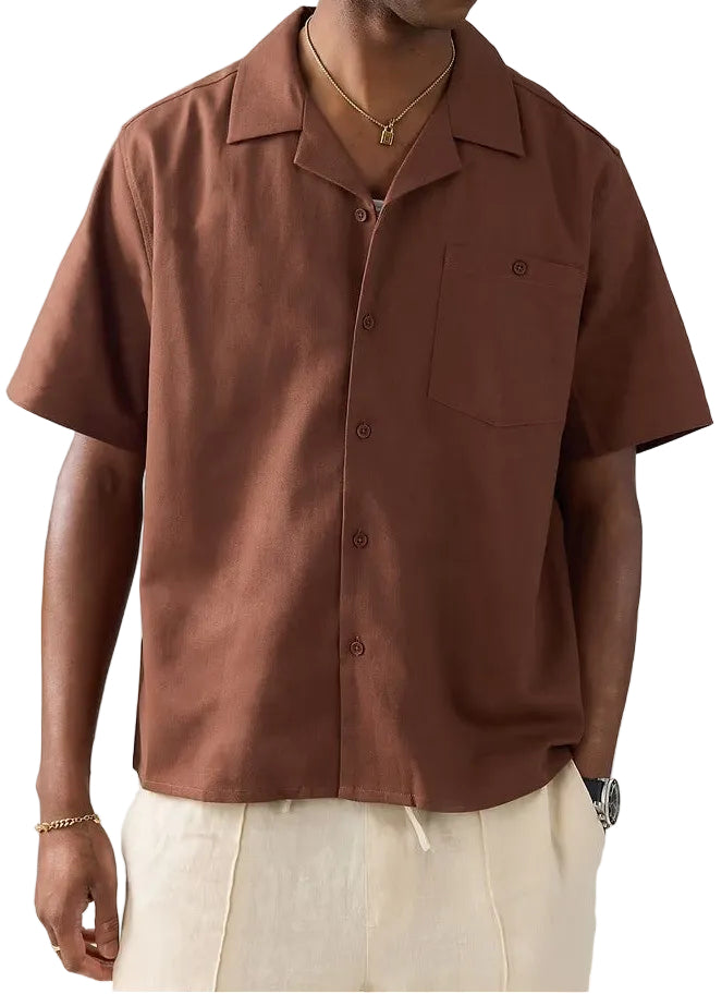 Man wearing a brown shirt and beige cap with a logo on a white background