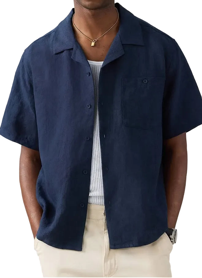 Man wearing a navy blue short-sleeve shirt over a white t-shirt on a white background