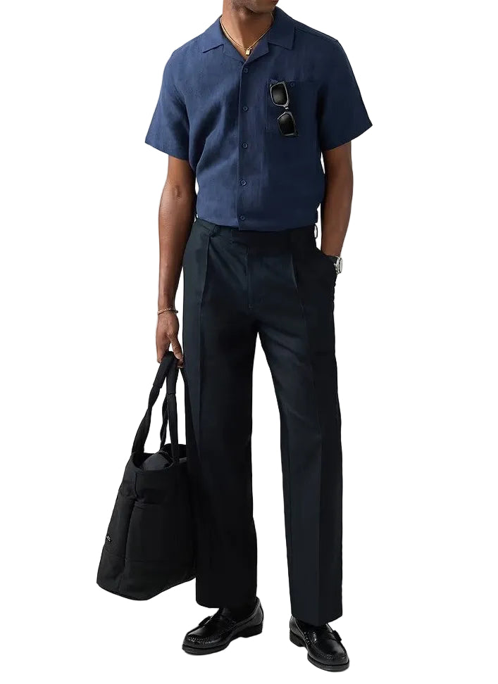 Man wearing a blue shirt and black pants holding a black bag on a white background