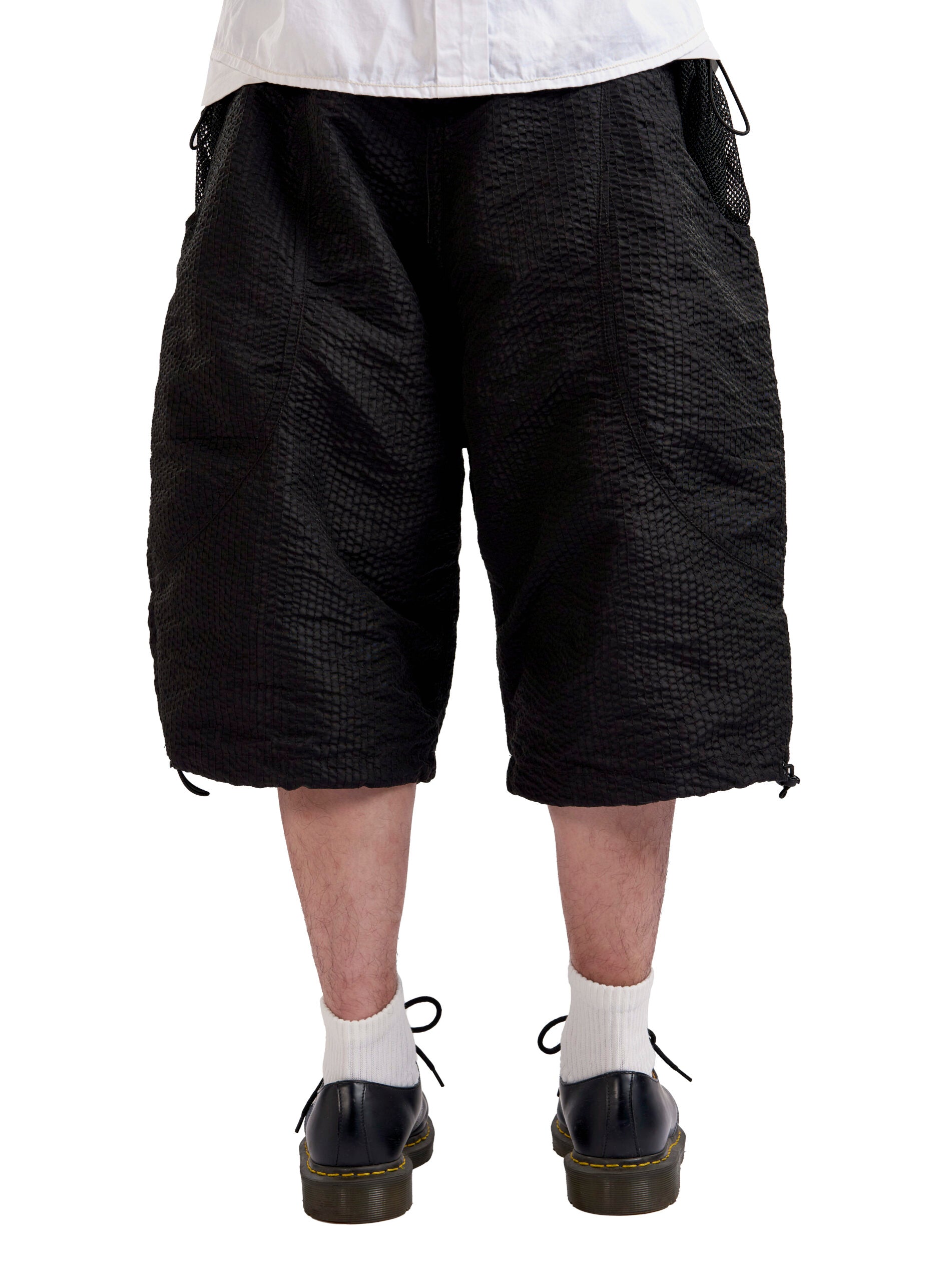 Person wearing black textured shorts on a white background