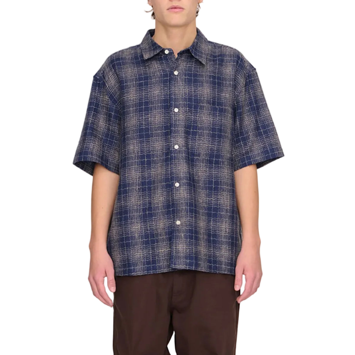 Person wearing a blue plaid shirt and brown pants on a white background