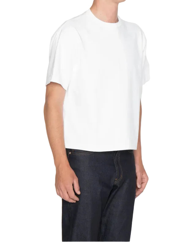 Person wearing a plain white t-shirt and dark jeans on a white background