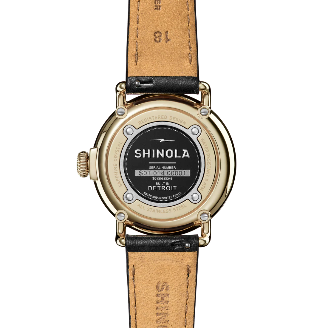 Back of a Shinola watch with a gold case and tan leather strap on a white background