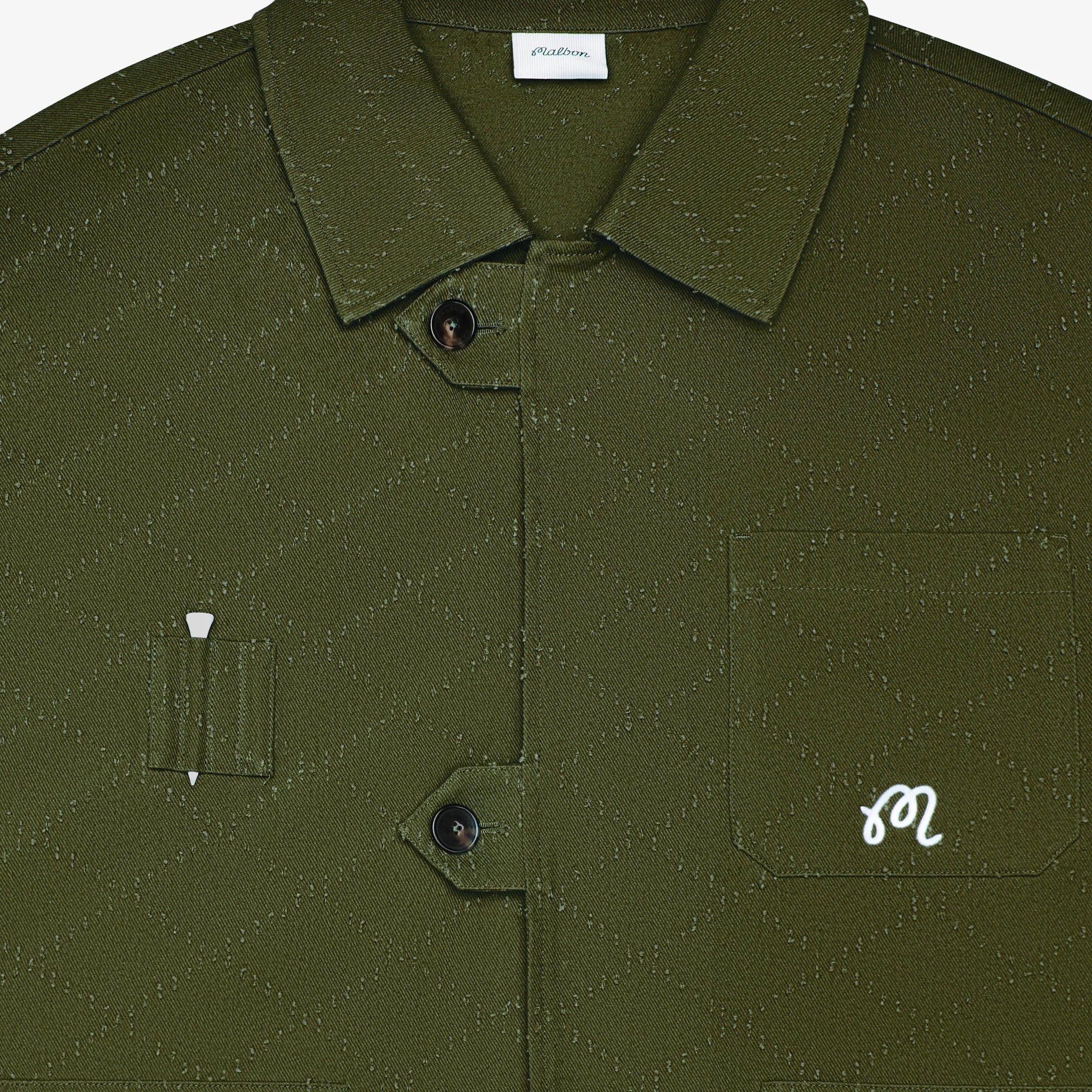 Close-up of a green textured shirt with a brand label on the collar.