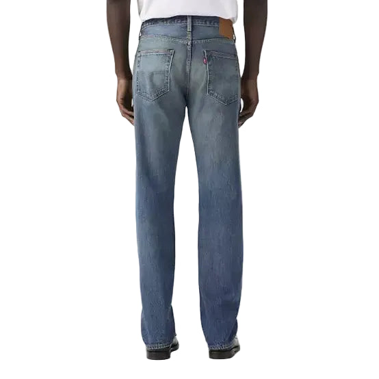 Person wearing blue jeans and a white t-shirt on a plain background
