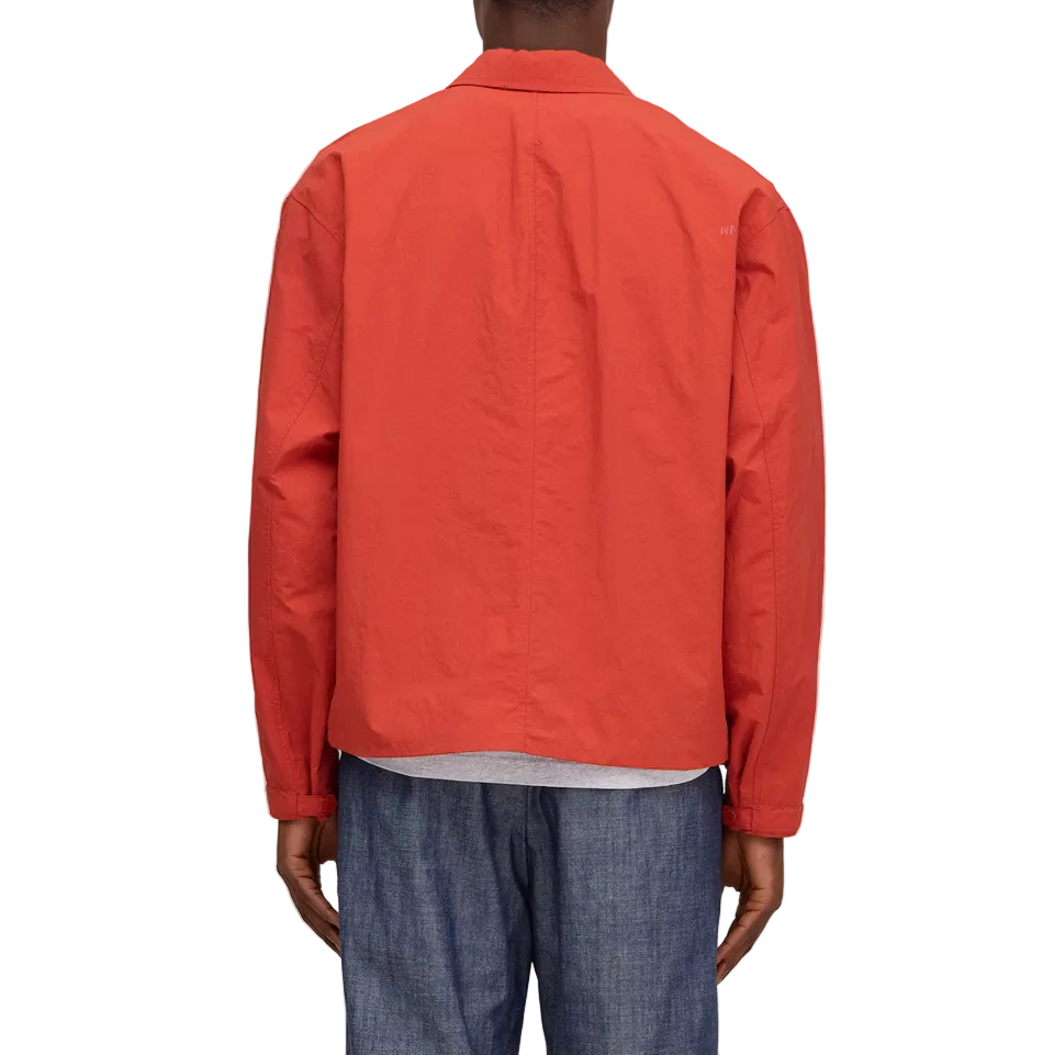 Person wearing a red jacket and blue jeans on a white background