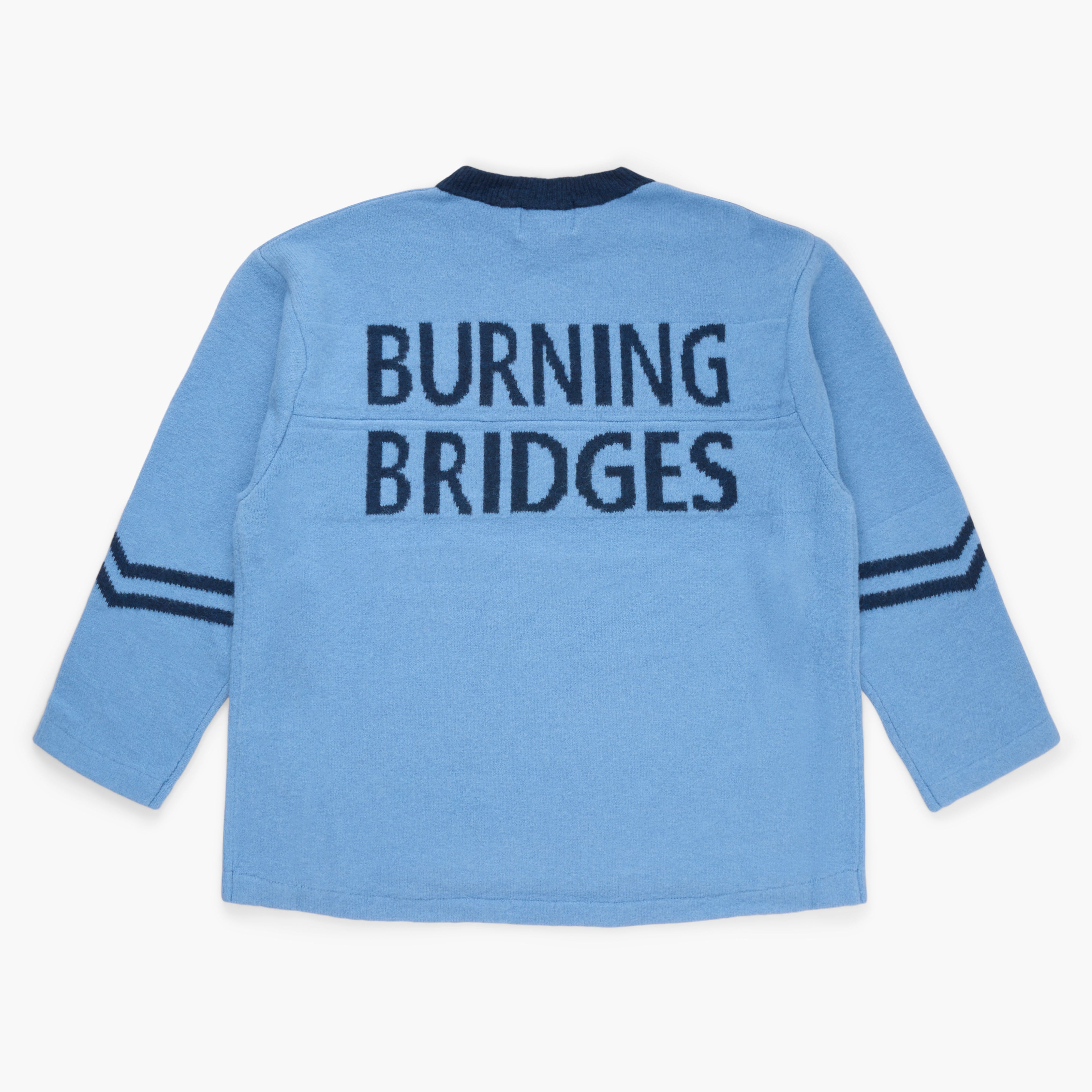 Blue sweater with 'Burning Bridges' knit on the back on a white background