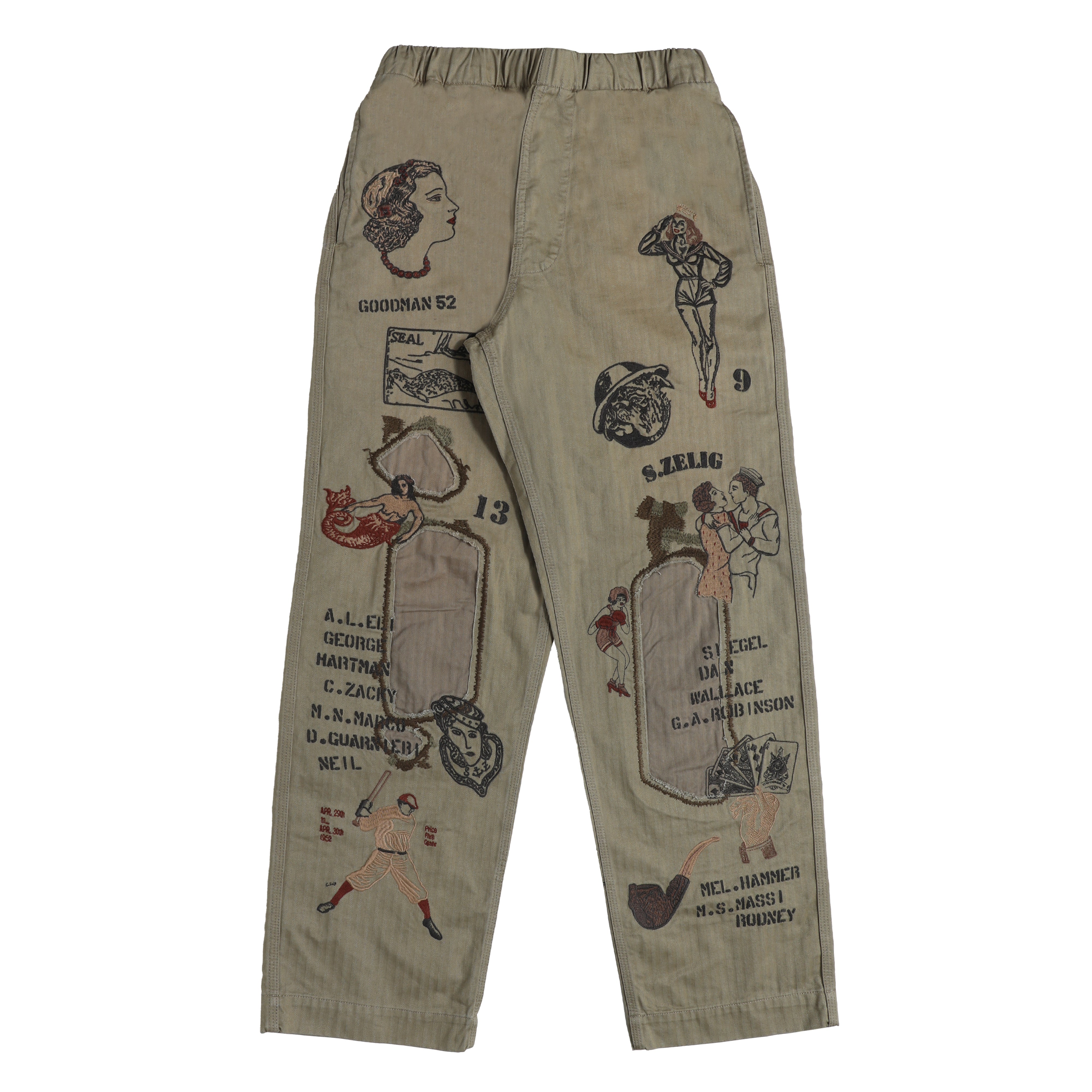 A pair of beige cargo pants featuring vintage pin-up girl illustrations and retro text graphics printed all over the fabric, shown against a plain white background.