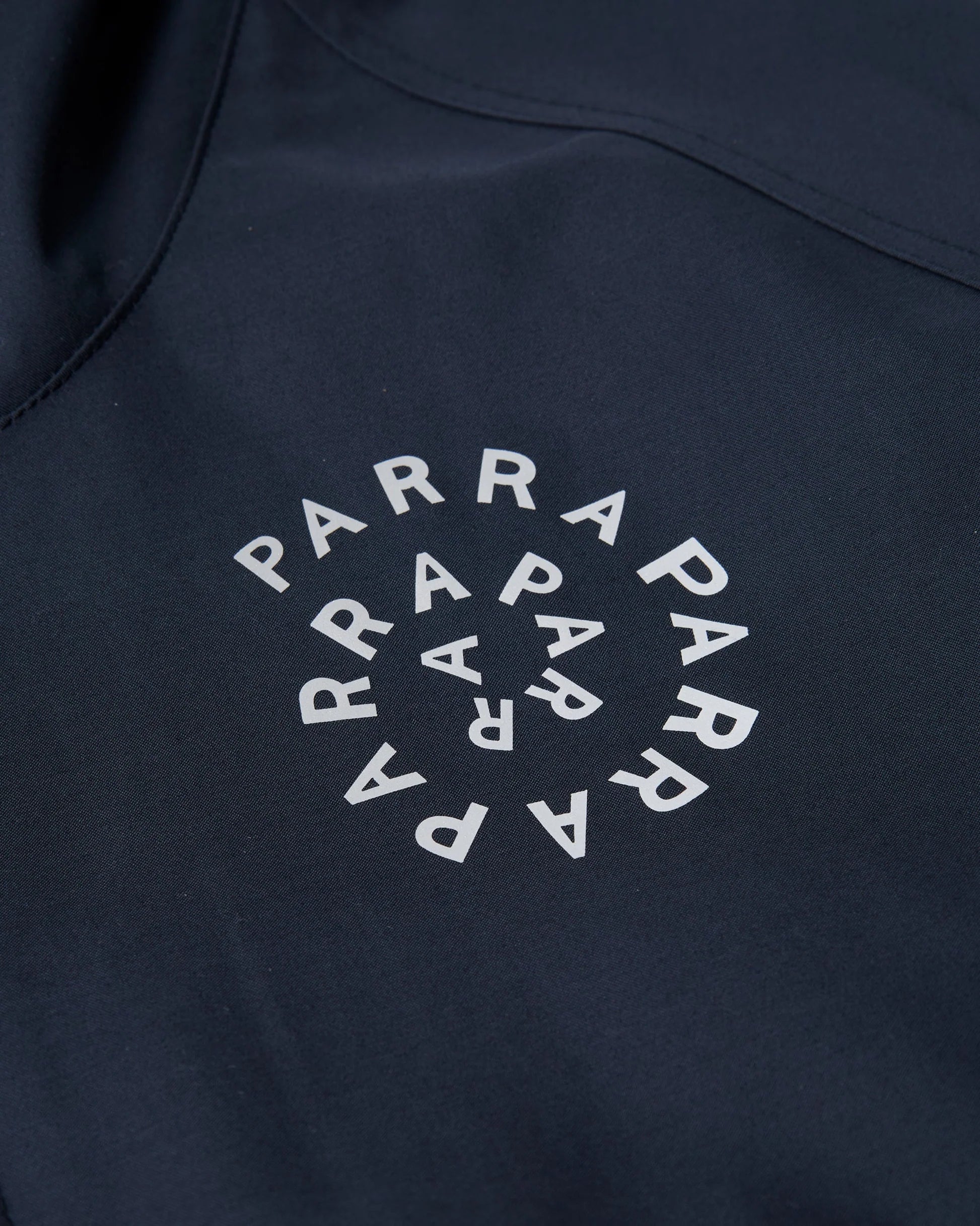 Close-up of a dark navy garment featuring a circular white 'PARRAPARRA' logo printed on the chest.