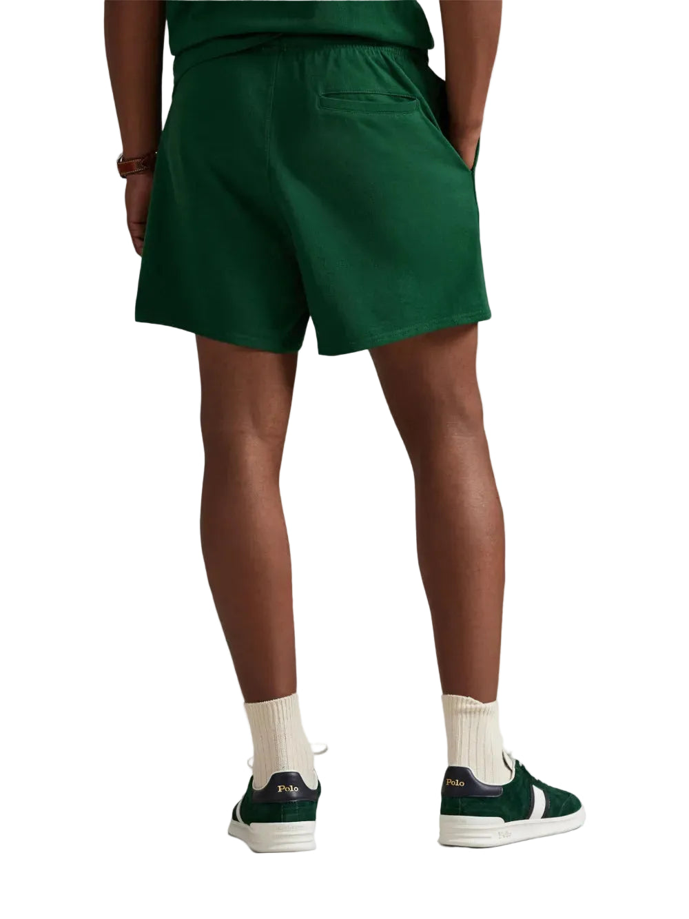 Person wearing green shorts and white socks with dark shoes on a white background