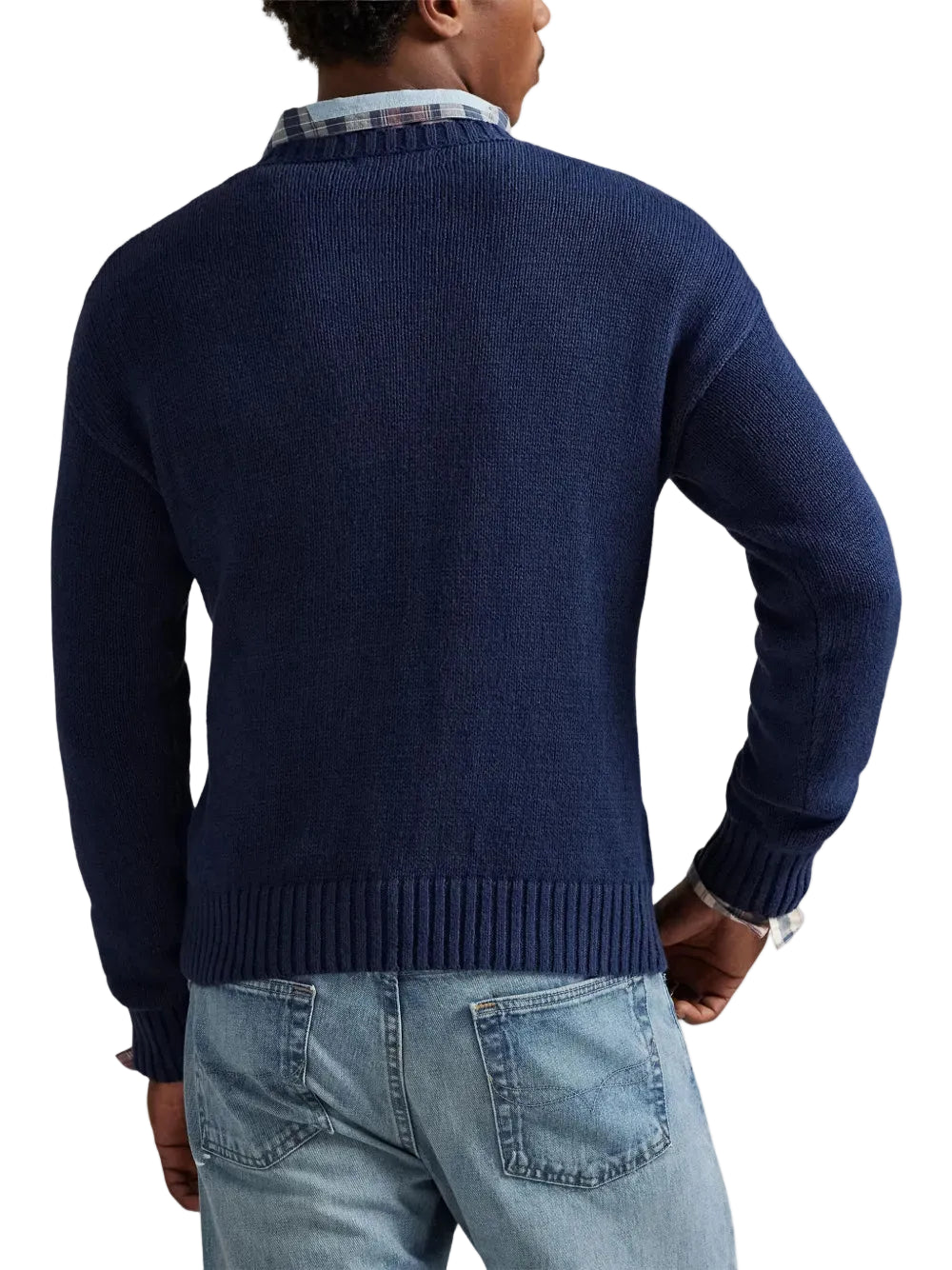 Person wearing a navy sweater and light blue jeans on a white background
