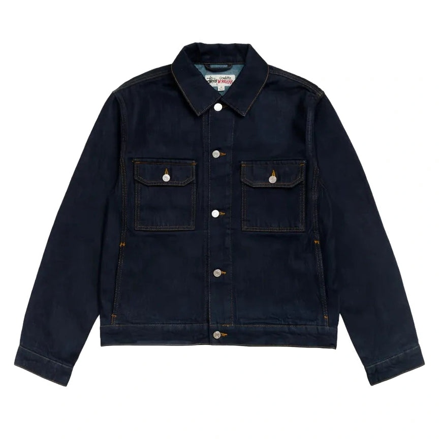 Front view of the Stüssy Trucker Denim jacket in rinsed indigo laid flat. A dark indigo denim jacket with gold contrast stitching, silver buttons and two flap chest pockets.