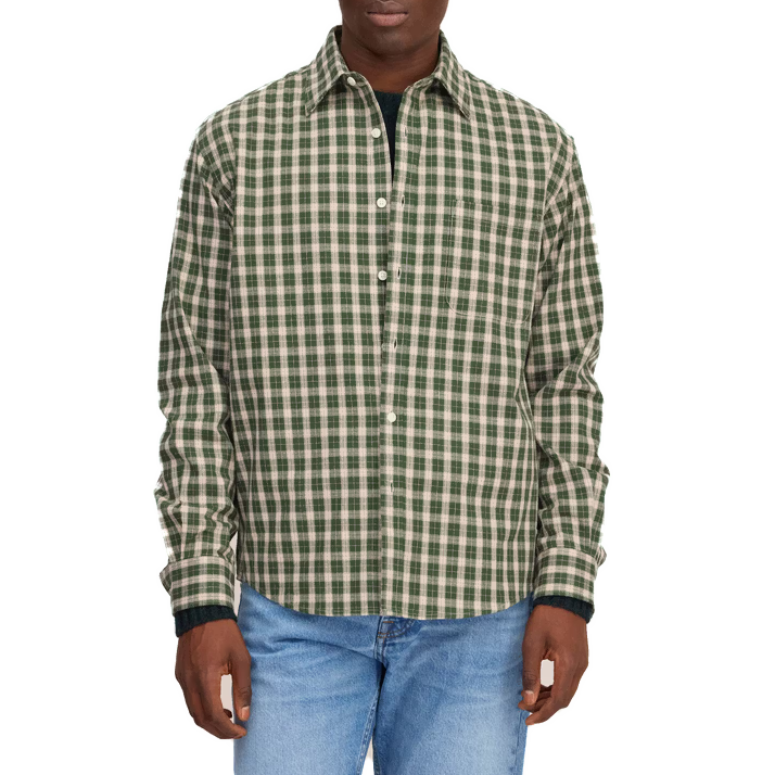 A model wears the green and cream check shirt open over a dark T-shirt with light-wash jeans.