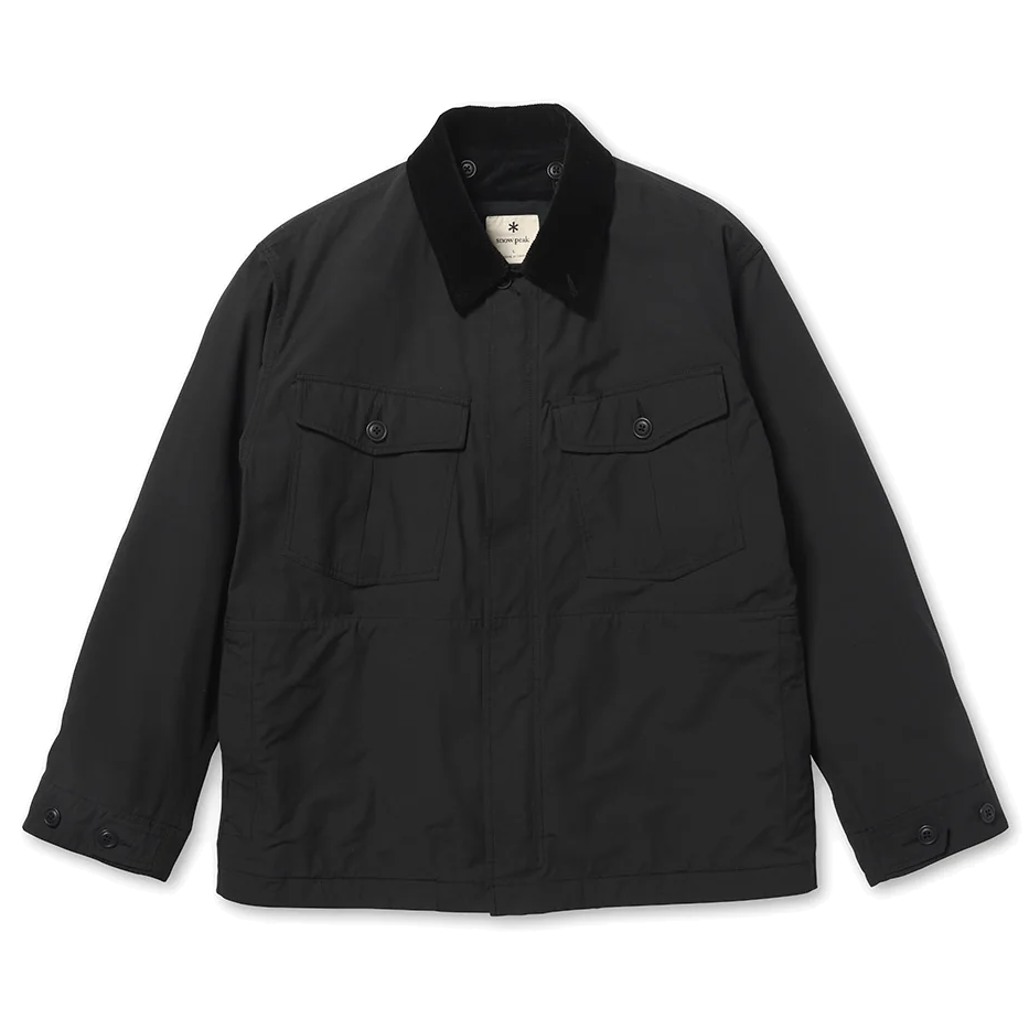 Front view of a black Snow Peak Hybrid Takibi Adjustable Jacket laid flat on white, showing the black corduroy collar, two flap chest pockets, covered front placket and button-tab cuffs.