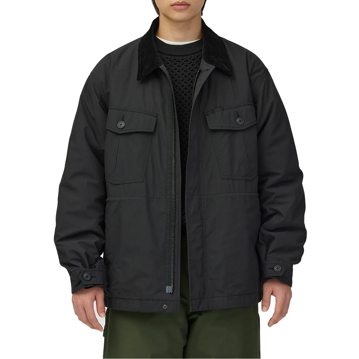 Waist-up view of a model wearing the black Snow Peak Hybrid Takibi Adjustable Jacket open, showing the corduroy collar, flap chest pockets and full-length front zip.