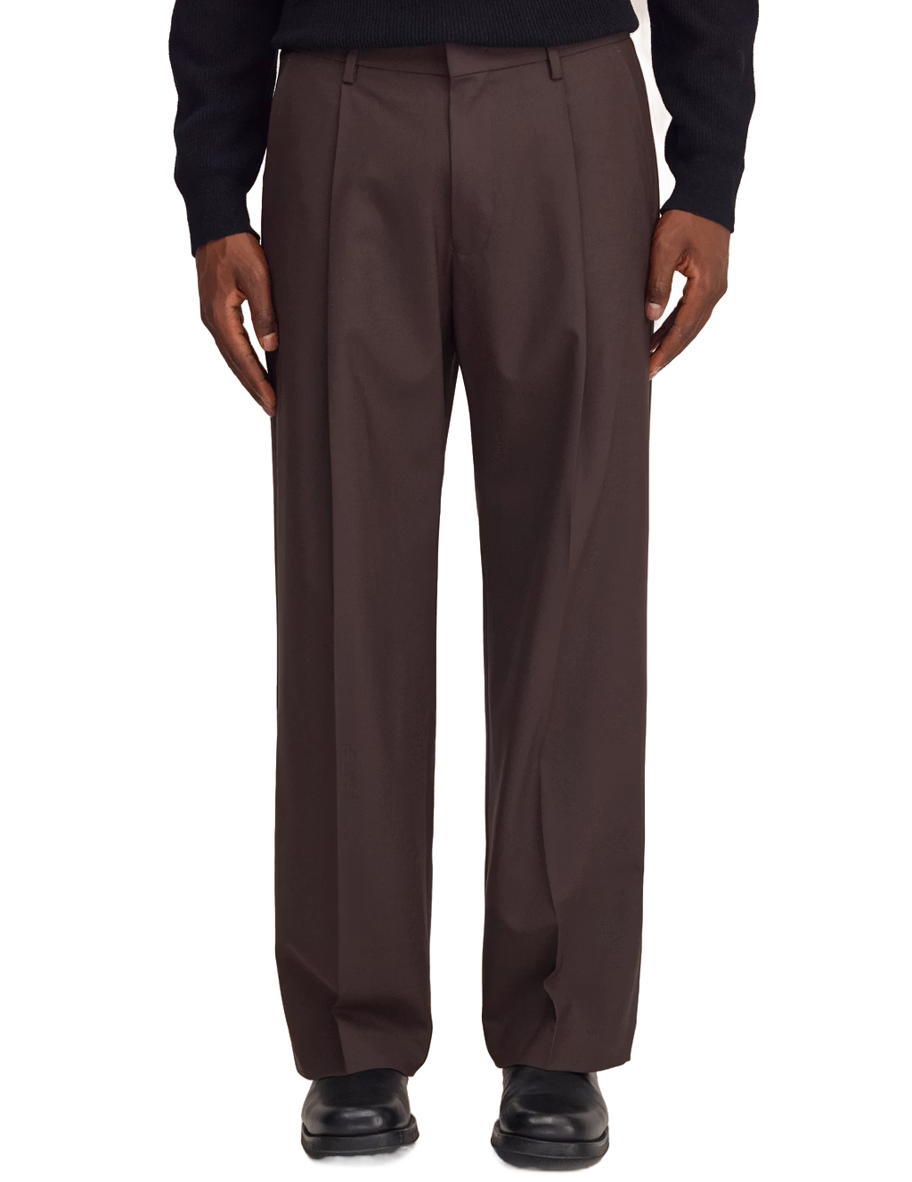 A person wearing dark brown wide-leg pleated trousers, a black long-sleeve top, and black shoes, shown from the chest down against a plain white background.