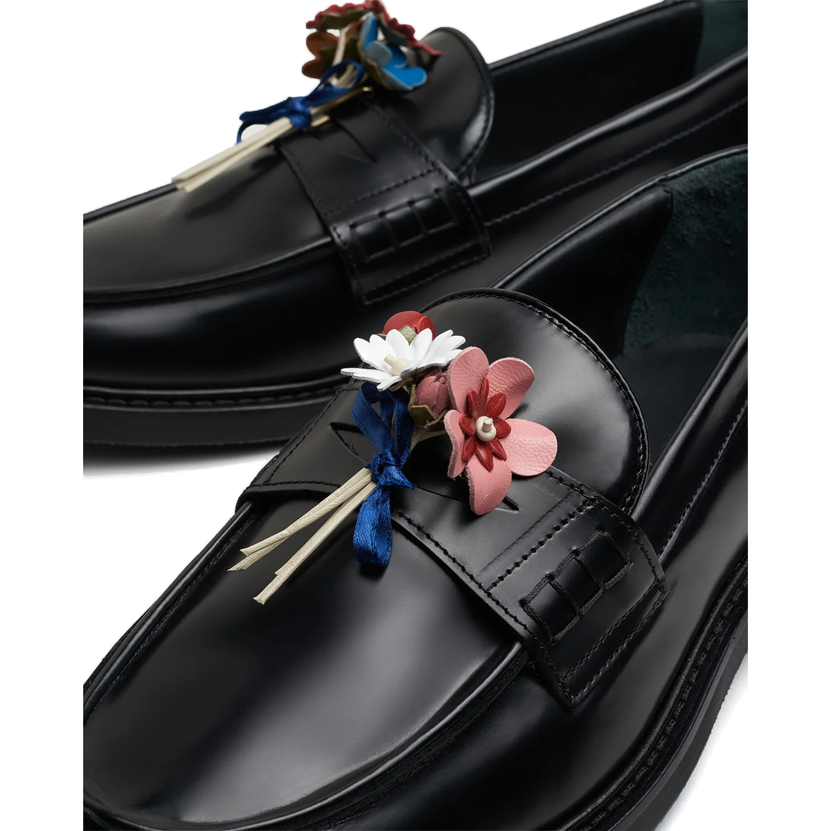 Close-up of the hand-made leather bouquet on a black Filling Pieces loafer, with pink, red, and white leather flowers tied with a blue satin ribbon.