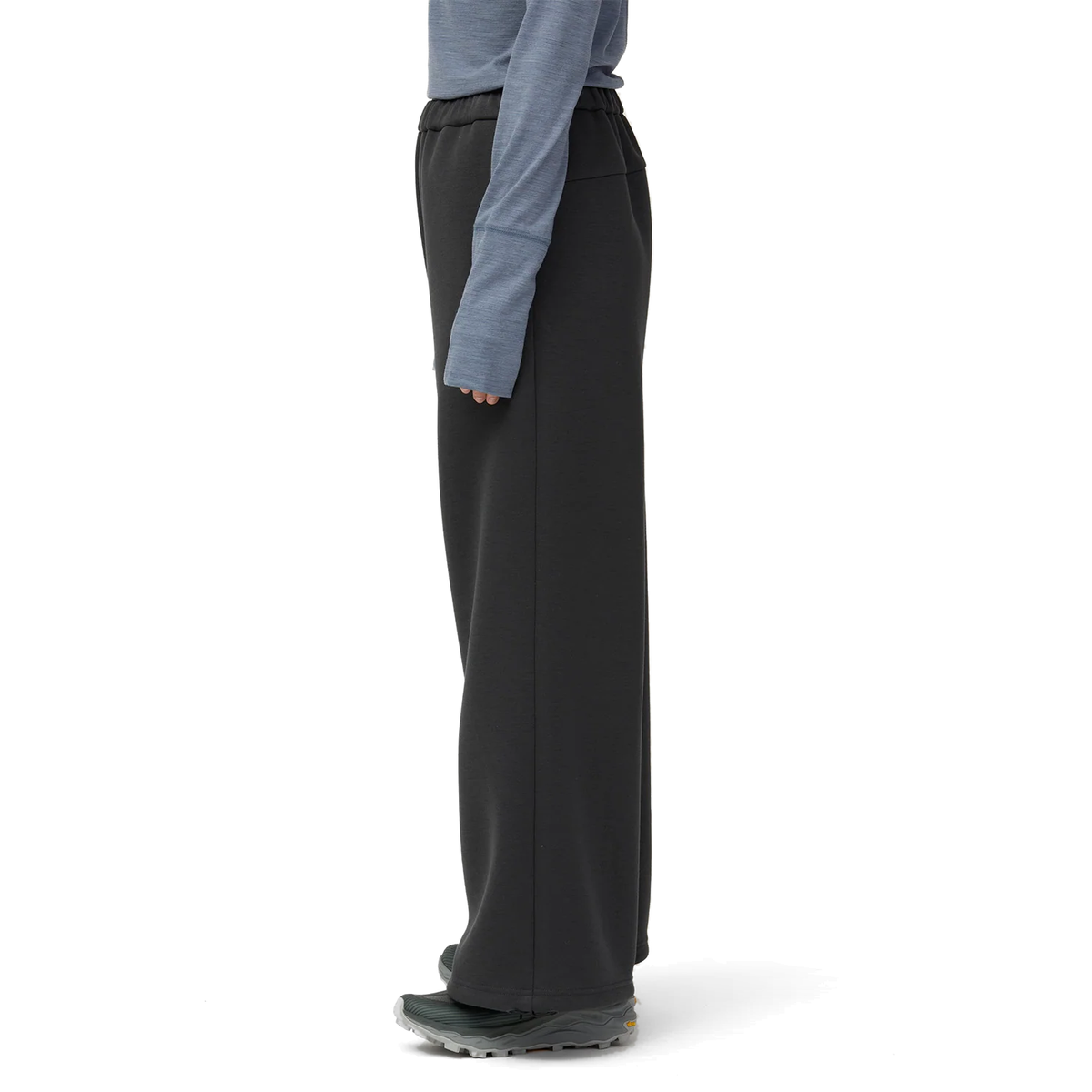 Side view of a model in charcoal Snow Peak Odor Control Women’s Pants, showing the elastic waist and the full-length wide leg falling over trail shoes.