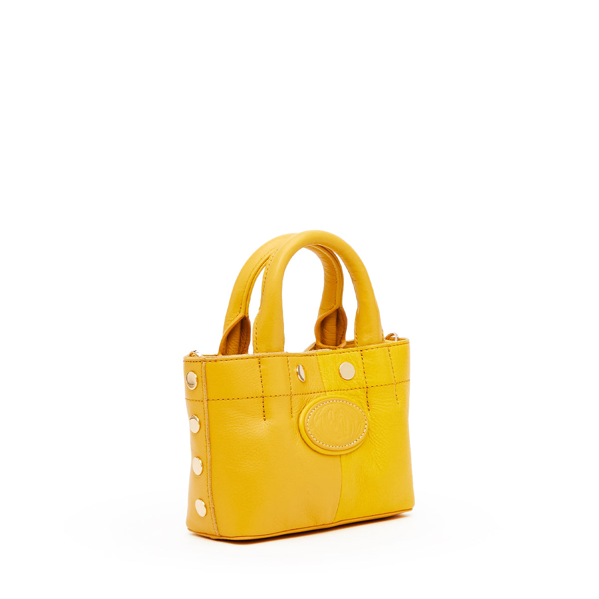 A small yellow leather handbag with double top handles, decorative gold-tone studs, and a circular embossed logo patch on the front, shown against a plain white background.