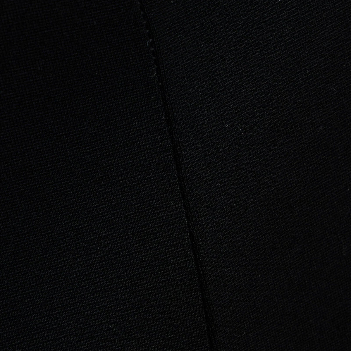 Close-up of a black textured fabric with a visible seam running vertically.