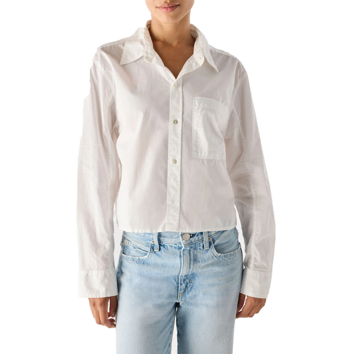Model wearing the AMO Ruth Crop Shirt in white, slightly open at the collar, with light-wash jeans, showing the cropped, relaxed fit.