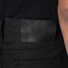 Black pants with a brand label featuring a stylized face and text.