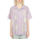 Person wearing a light purple shirt with graphic designs on a white background