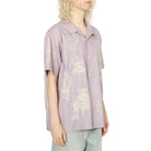 Person wearing a light purple shirt with graphic designs on a white background
