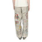 Person wearing a white t-shirt and patterned beige pants on a white background