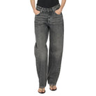 Person wearing black tank top and gray high-waisted jeans on a white background