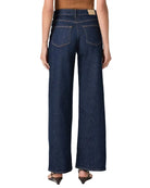 Person wearing dark blue wide-leg jeans on a white background