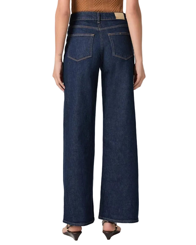 Person wearing dark blue wide-leg jeans on a white background