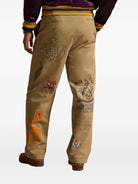 Beige pants with patches and logos on a white background