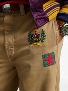 Beige pants with embroidered patches on a white background