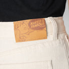 Close-up of a label on a pair of white pants with 'Naked & Famous Denim' branding.