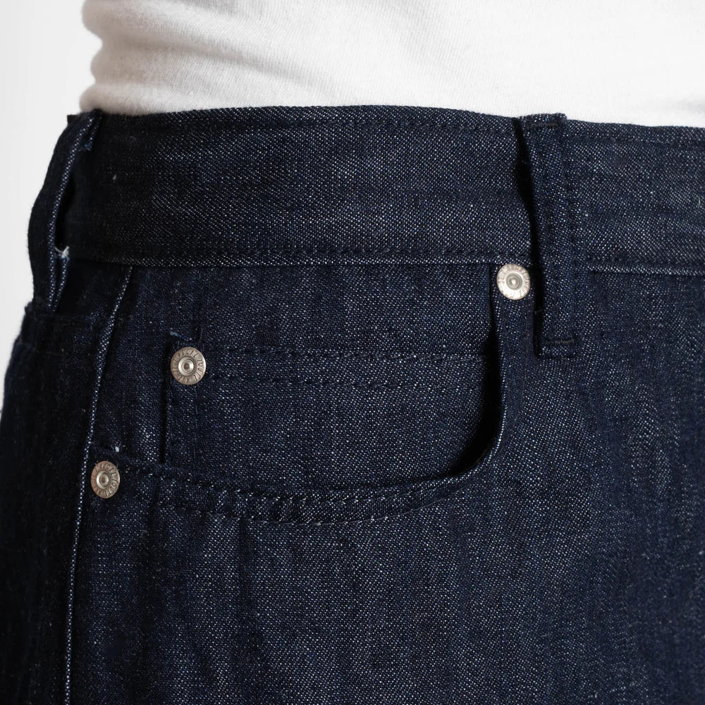 Close-up of dark blue denim pants with button details.