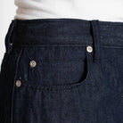Close-up of dark blue denim pants with button details.