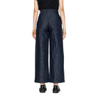 Person wearing dark blue wide-leg jeans on a white background