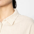 Close-up of a person wearing a light-colored shirt with a collar against a neutral background