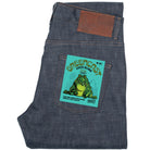 Folded denim jeans with a green label featuring a frog design on a white background