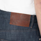 Close-up of blue jeans with a brown leather patch featuring a brand logo.
