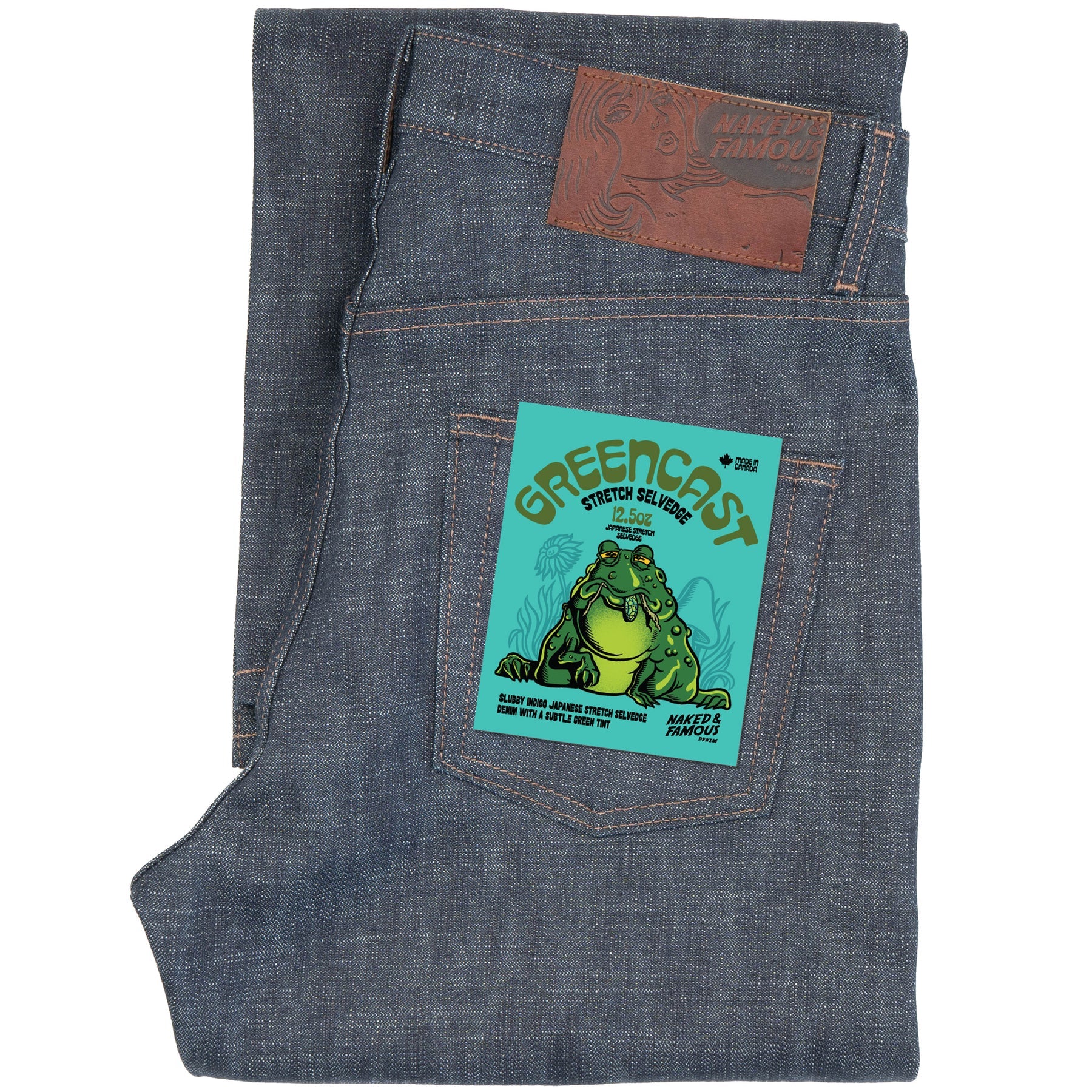 Folded blue denim jeans with a green frog label on a white background