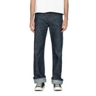 Person wearing dark blue jeans with a plain background