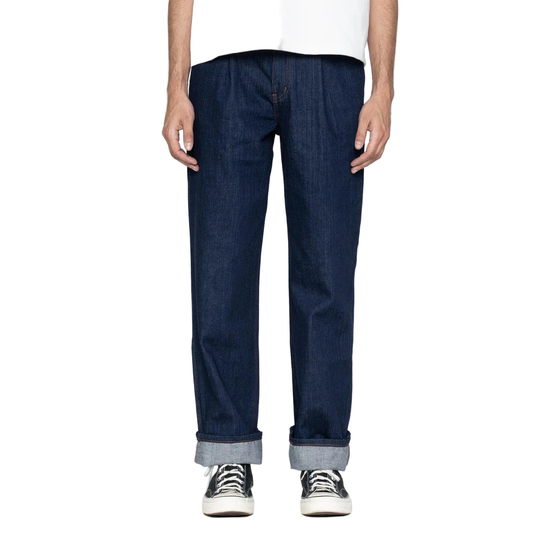 Person wearing dark blue jeans and black sneakers on a white background