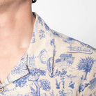 Close-up of a person wearing a blue and white patterned shirt with a plain background