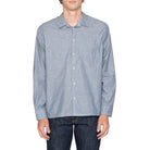 Man wearing a light blue striped shirt and dark jeans on a white background