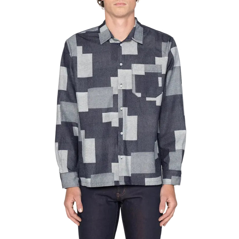 Person wearing a patterned shirt with geometric design on a plain background