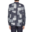 Person wearing a patterned shirt with geometric design on a white background